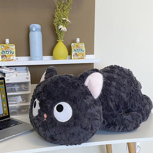 a fluffy black cat plushie laying on the table