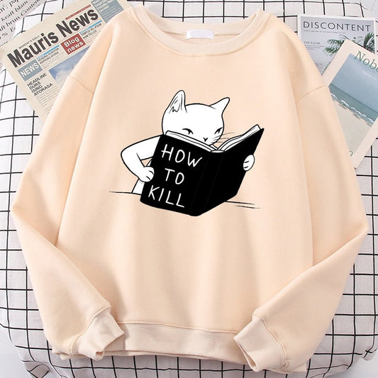 beige-colored sweatshirt with a cartoon cat reading a book titled "How to Kill."