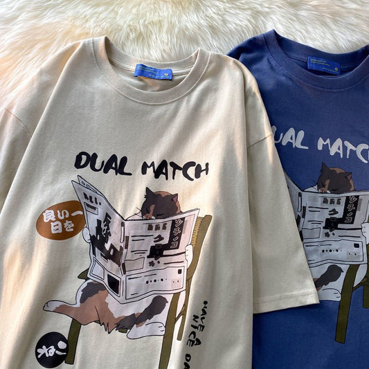 high quality streetwear t shirt in off white and blue color featuring a japanese cat print of a cat reading newspaper