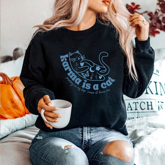 a woman wearing a black 'karma is a cat' sweatshirt that looks cute and vintage