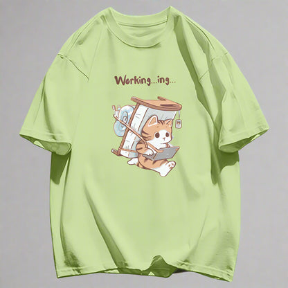 Light green cartoon cat theme t-shirt with a cat character carrying a mattress and 'Working...ing' text representing a work from home cat