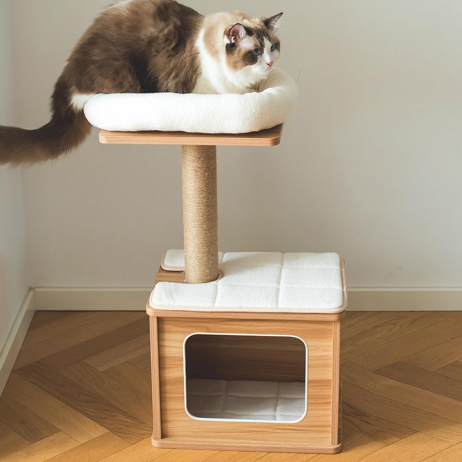 Cat sitting on a 2 level elevated wooden cat tree with white cushioned platforms