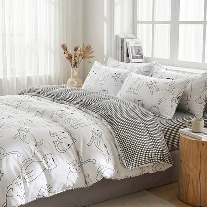 Bed with white bedding featuring black cat illustrations, checkered blanket, and wooden side table.