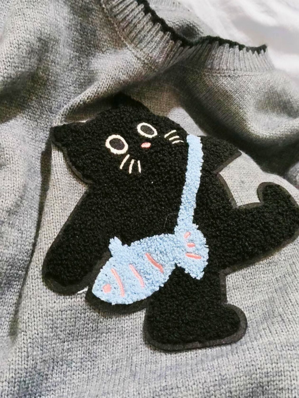 high quality detail of an embroidery black cat from a women's sweater