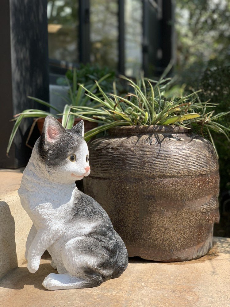an adorable realistic outdoor cat statue of a tabby cat beside a vase