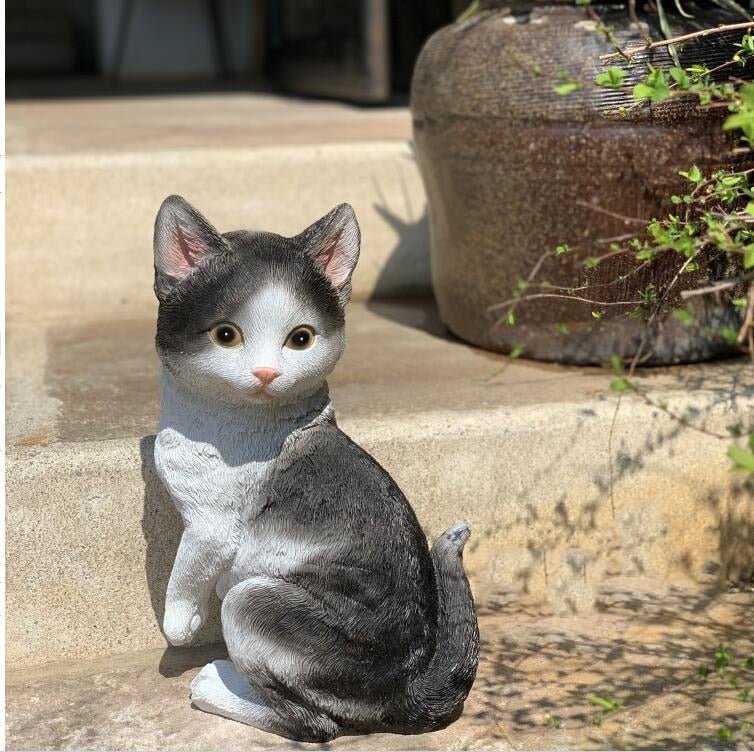 a realistic looking cat sculpture of a grey tabby cat as outdoor garden decoration
