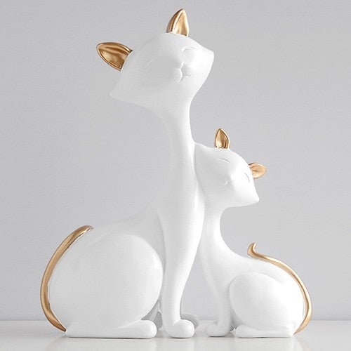 a pair of white cat sculpture with golden ears and tails