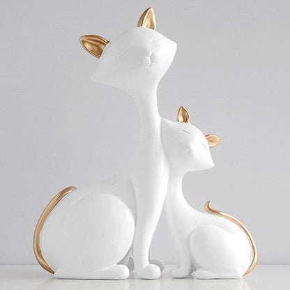 a pair of white cat sculpture with golden ears and tails