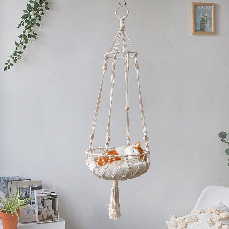 cat sleeping in a white color cat bed that is hung from the ceiling 