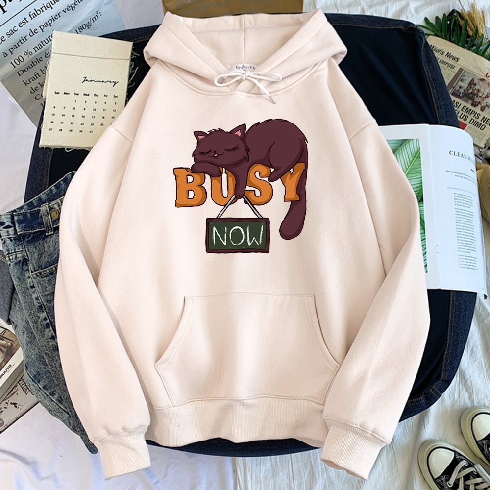 a beige color hoodie with a cute brown cat sleeping on a busy now sign