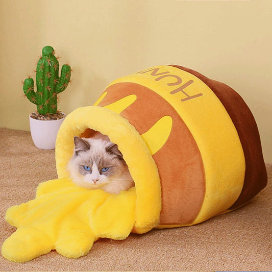 a cat laying inside a hunny pot shape cat bed and looks like honey was spilt over
