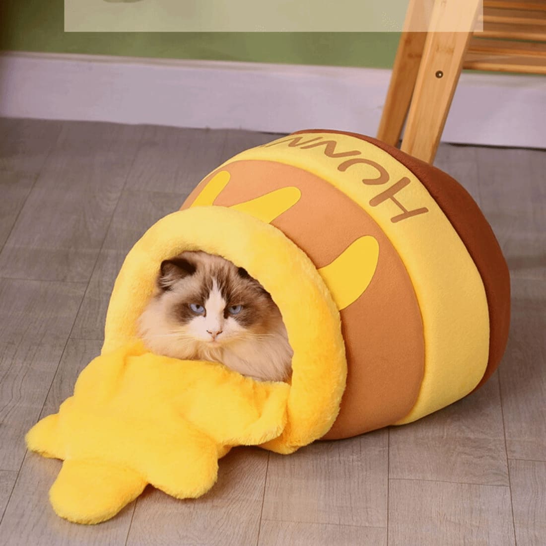 a cat hiding inside a hunny pot shape cat bed in yellow color and looks so adorable just like honey was spilt over