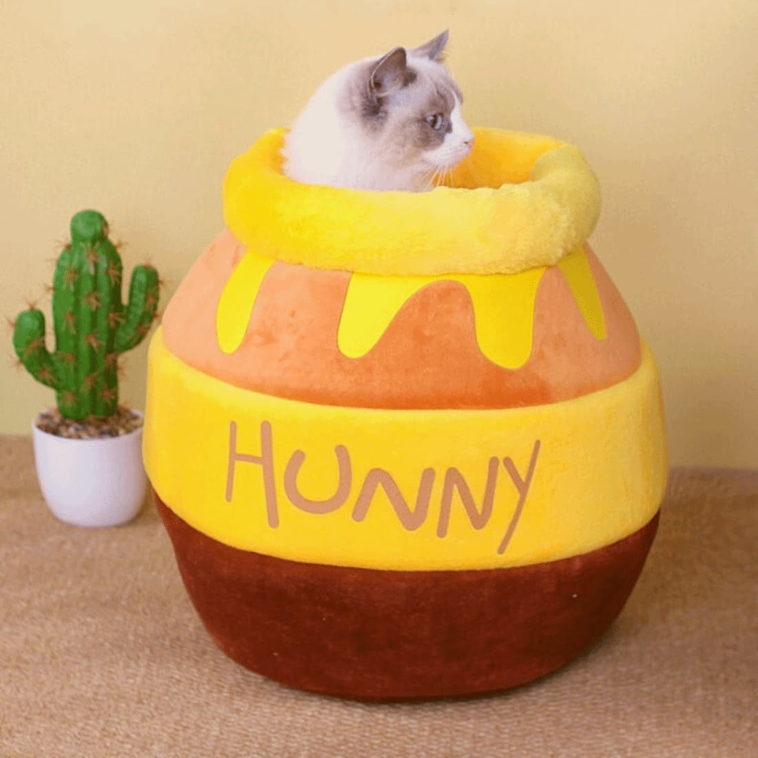 a cat inside a yellow color honey jar quoted with hunny cat bed words