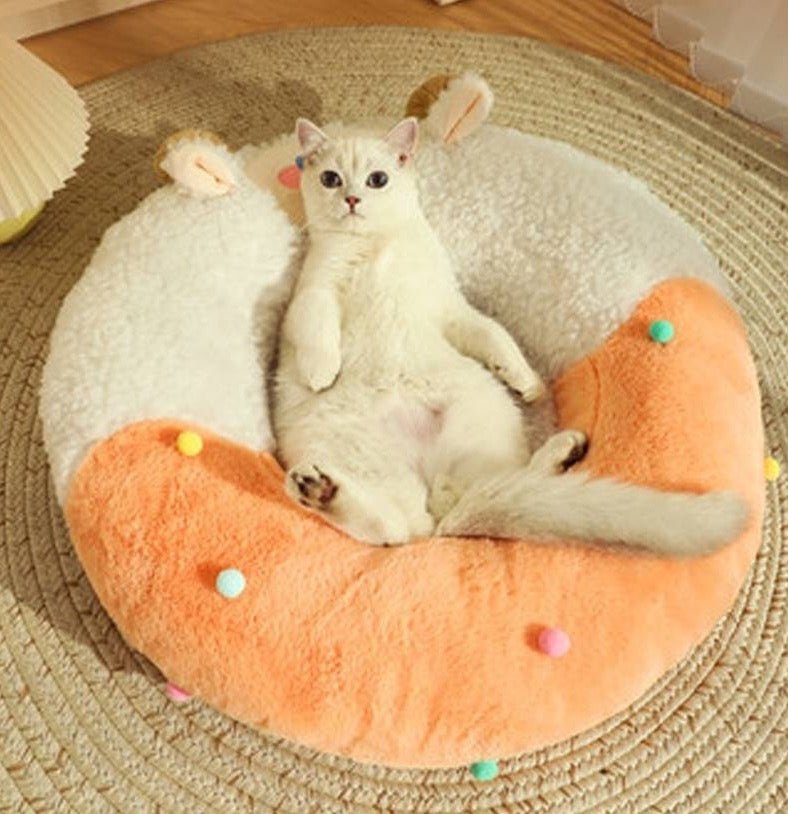 white cat laying on a round cat bed with a goat design that looks comfy and adorable