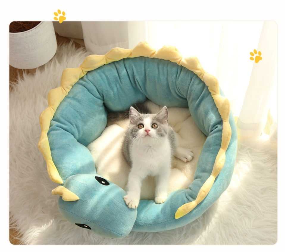 cat sitting on a round shape cat bed with a unique dinosaur design  that looks cute