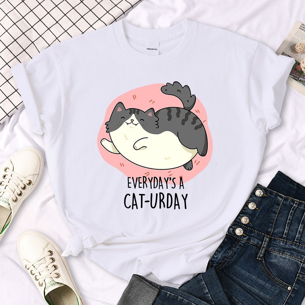 A happy British Shorthair cat jumping happily with smile printed on a women's T-shirt, called 'Everyday is a Cat-urday' from Meowgicians