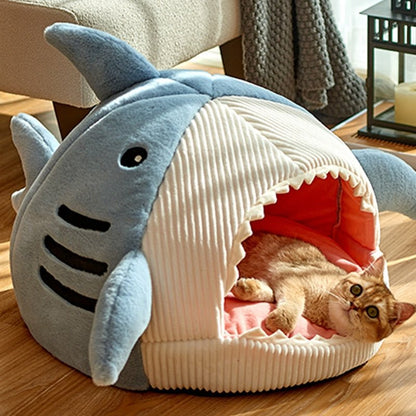 cat sleeping inside a funny looking cat bed with a shark design and has an enclosed space