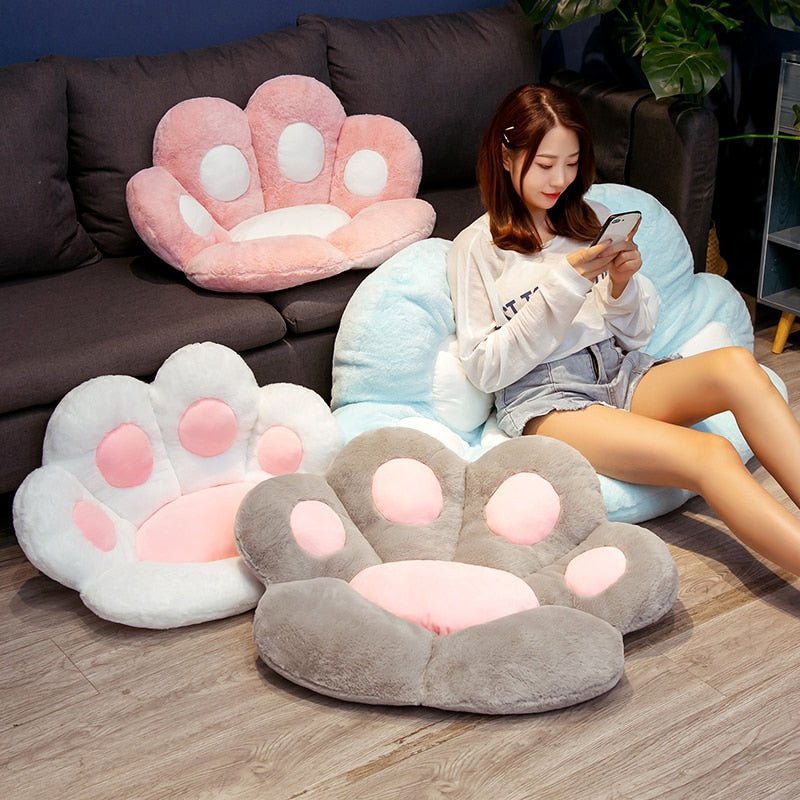 a lady sitting on a fluffy, colorful Giant Cat Paw Shaped Chair Cushion Plush, it is perfect for adding a cute, kawaii touch to any living space
