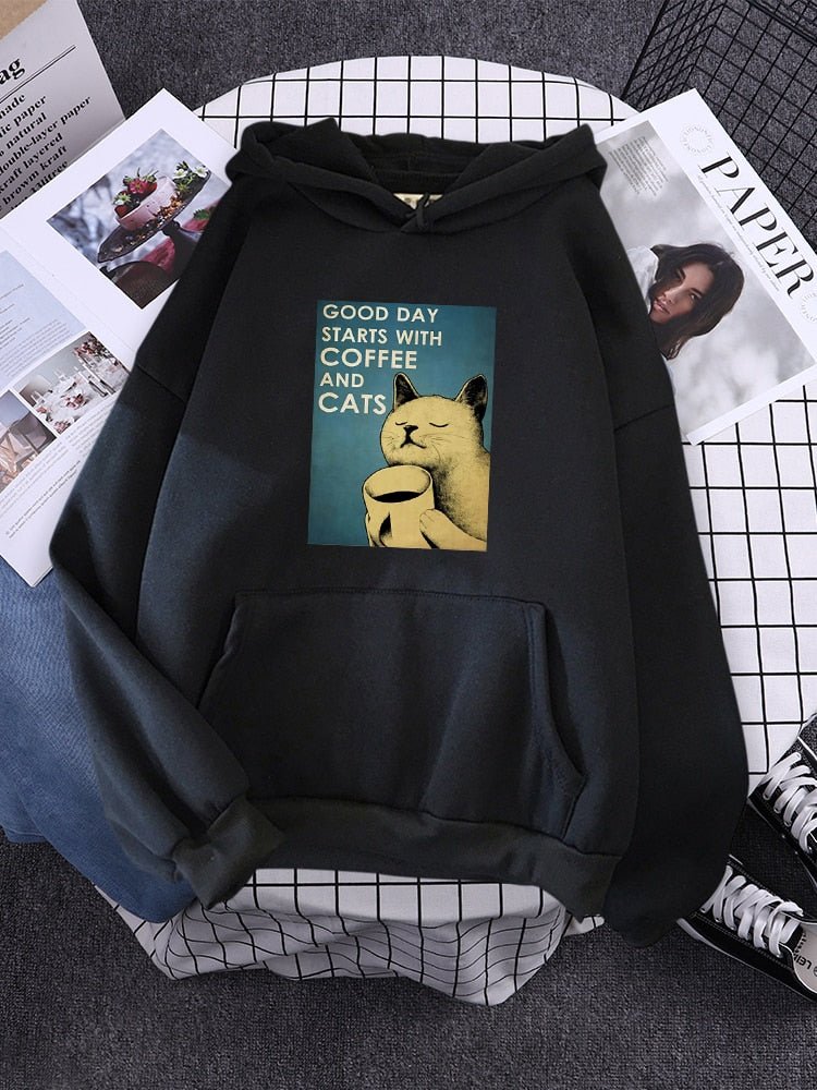 a black hoodie featuring a picture of cat and coffee which are the most two essential things in the morning