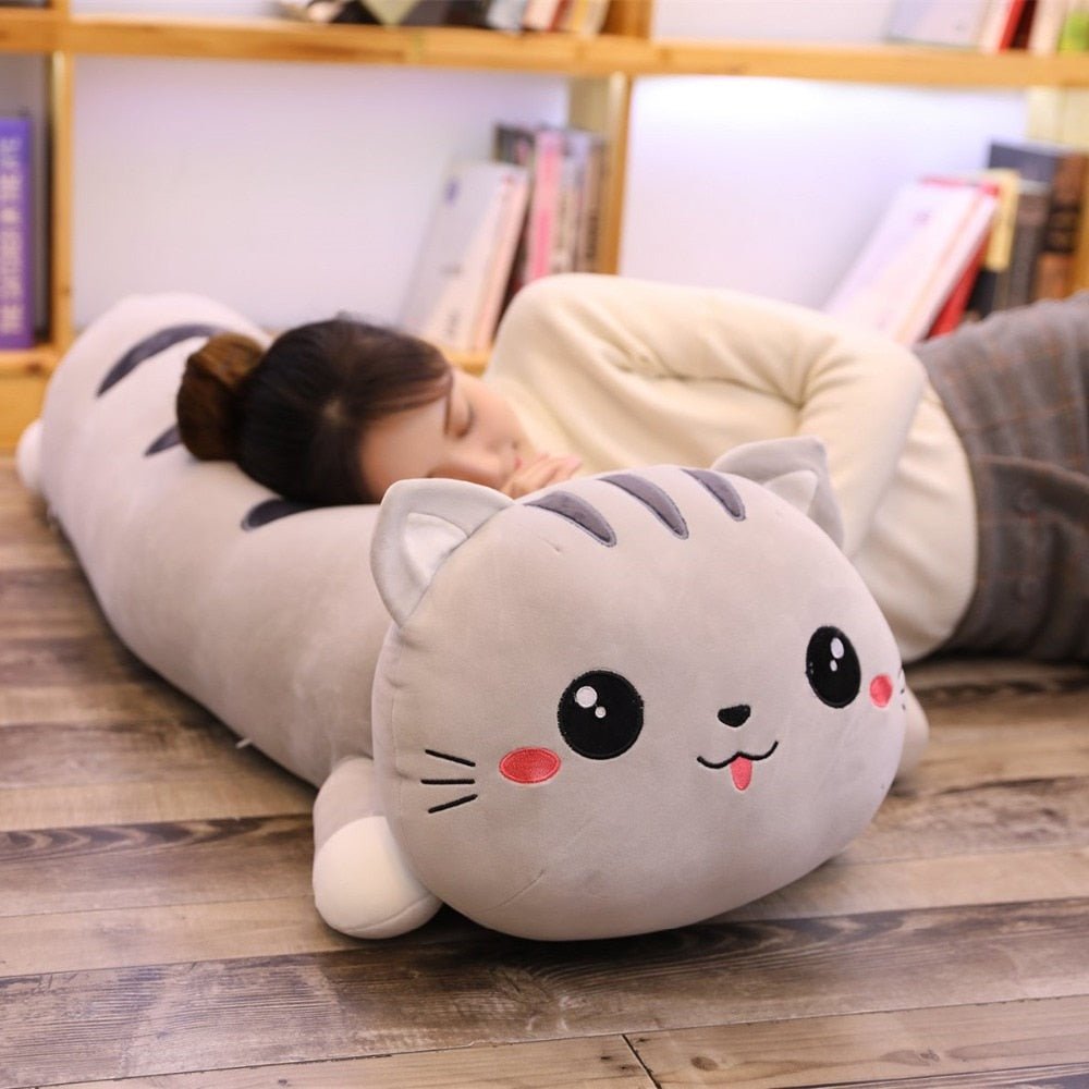 a woman sleeping on a long gray cat stuffed animal