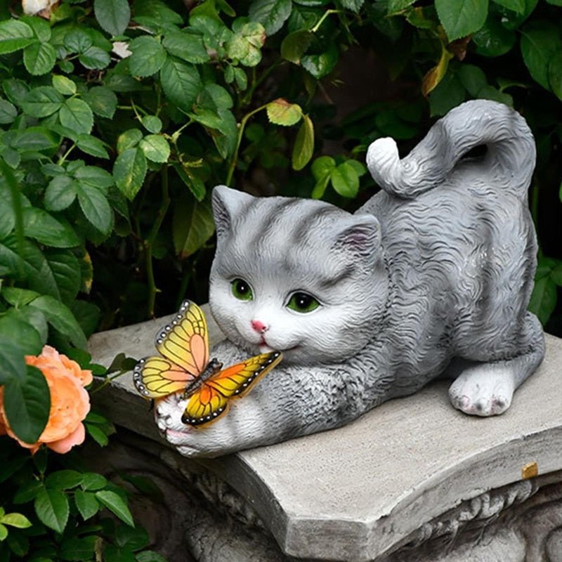 a cat statue holding a beautiful butterfly at an outdoor garden for home decor