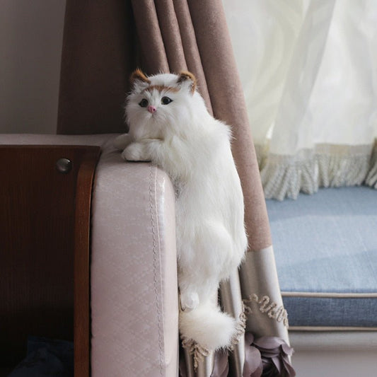 a ragdoll cat plushies hanging in a couch as home decor