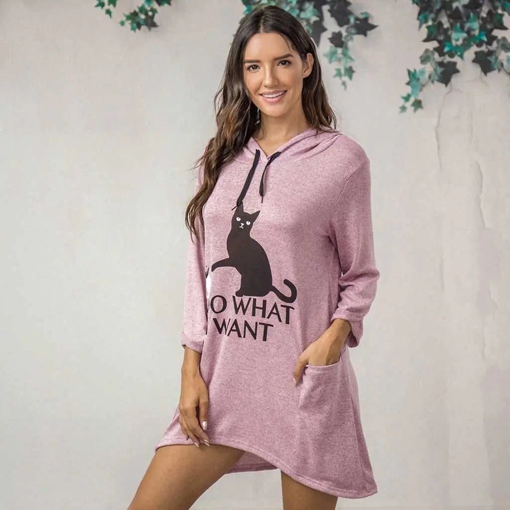 a woman wearing a cute pink hoodie that is oversized and made for cat moms with a picture of a black cat saying it knows what it wants