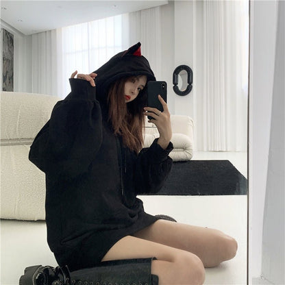 a girl wearing a black color japanese cat hoodie that looks kawaii