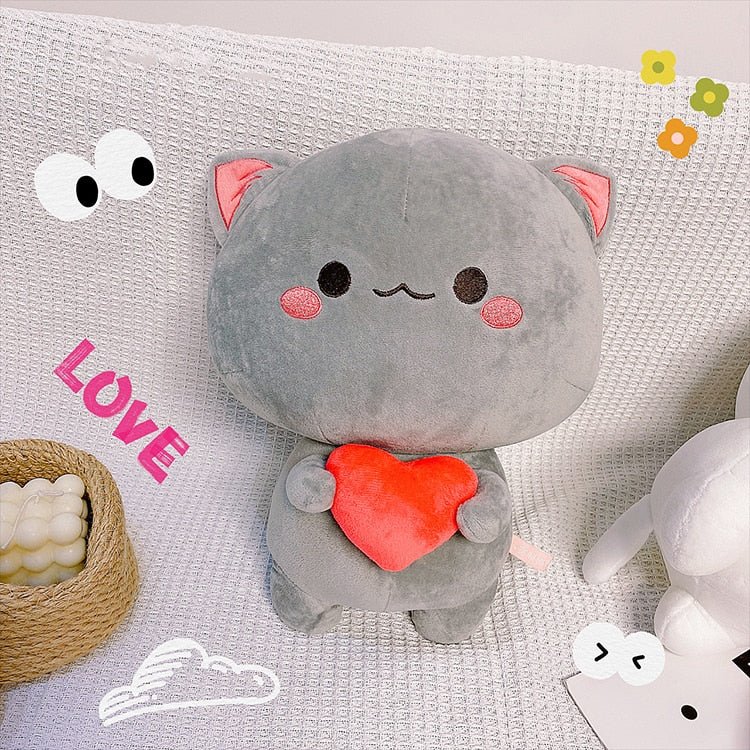 a grey cat plush holding a heart