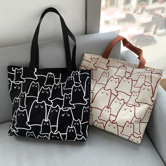 beige color and black color cat tote bag with cute cat cartoon on it putting on a sofa