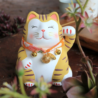 a tiger cat figure with bells and necklace waving to people