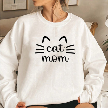 a woman wearing a beige color girls cat sweatshirt with the word cat mom