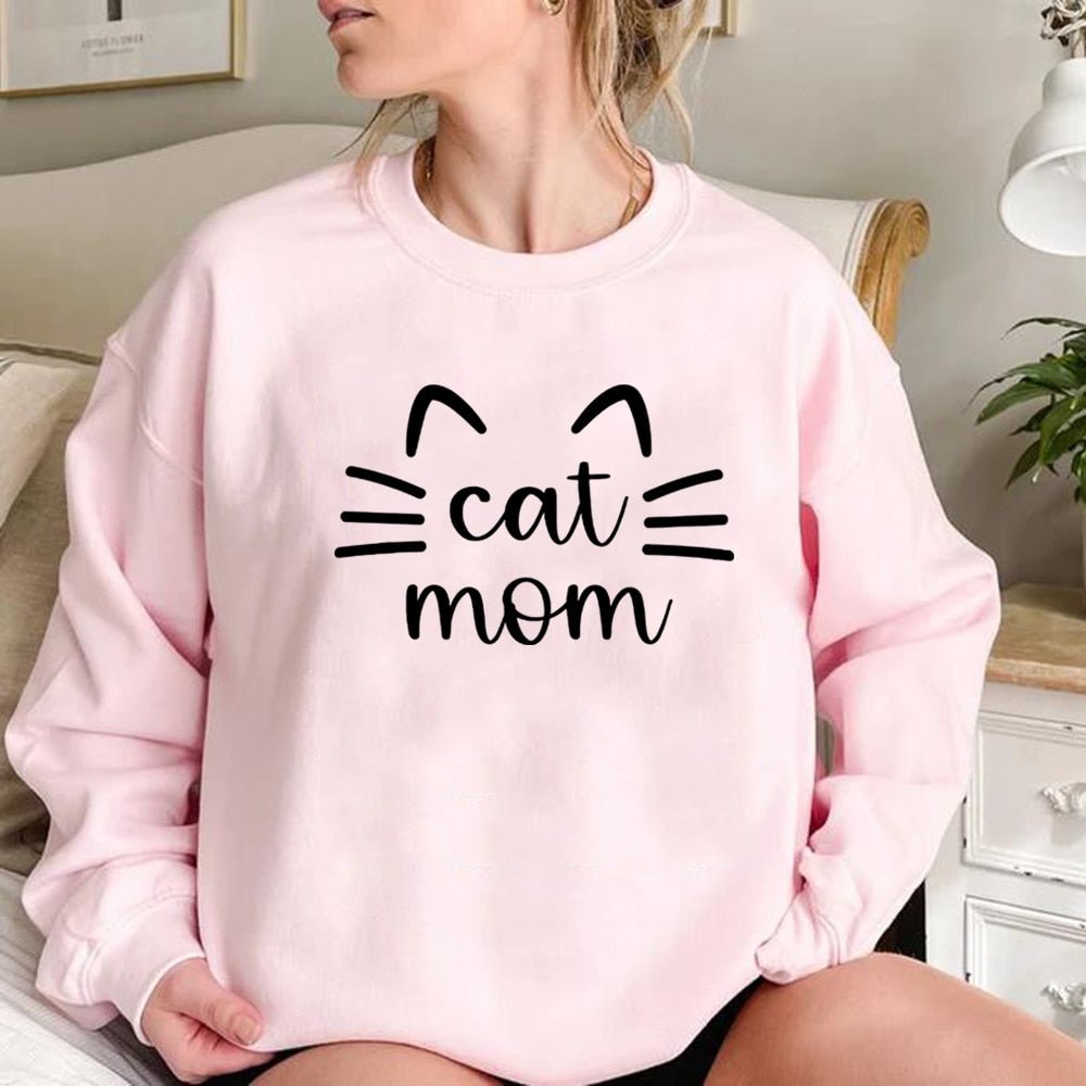 a woman wearing a pink cat mom sweatshirt with word cat mom