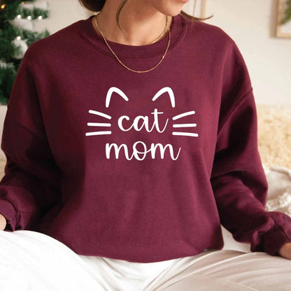 a woman wearing a maroon womens cat sweatshirt with the word cat mom