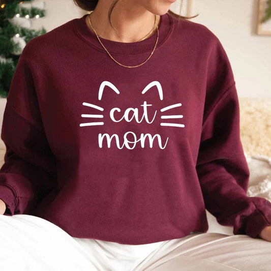 a woman wearing a maroon womens cat sweatshirt with the word cat mom