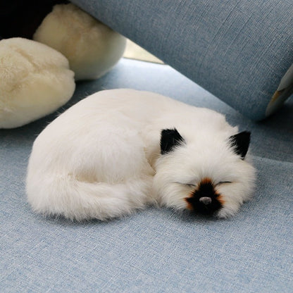 super realistic stuffed cat of a siamese cat sleeping on sofa