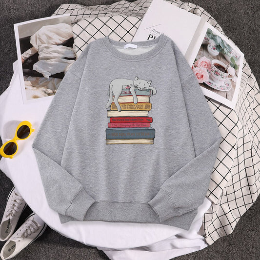 a grey cat print sweater with a picture of a cat sleeping on a stack of books