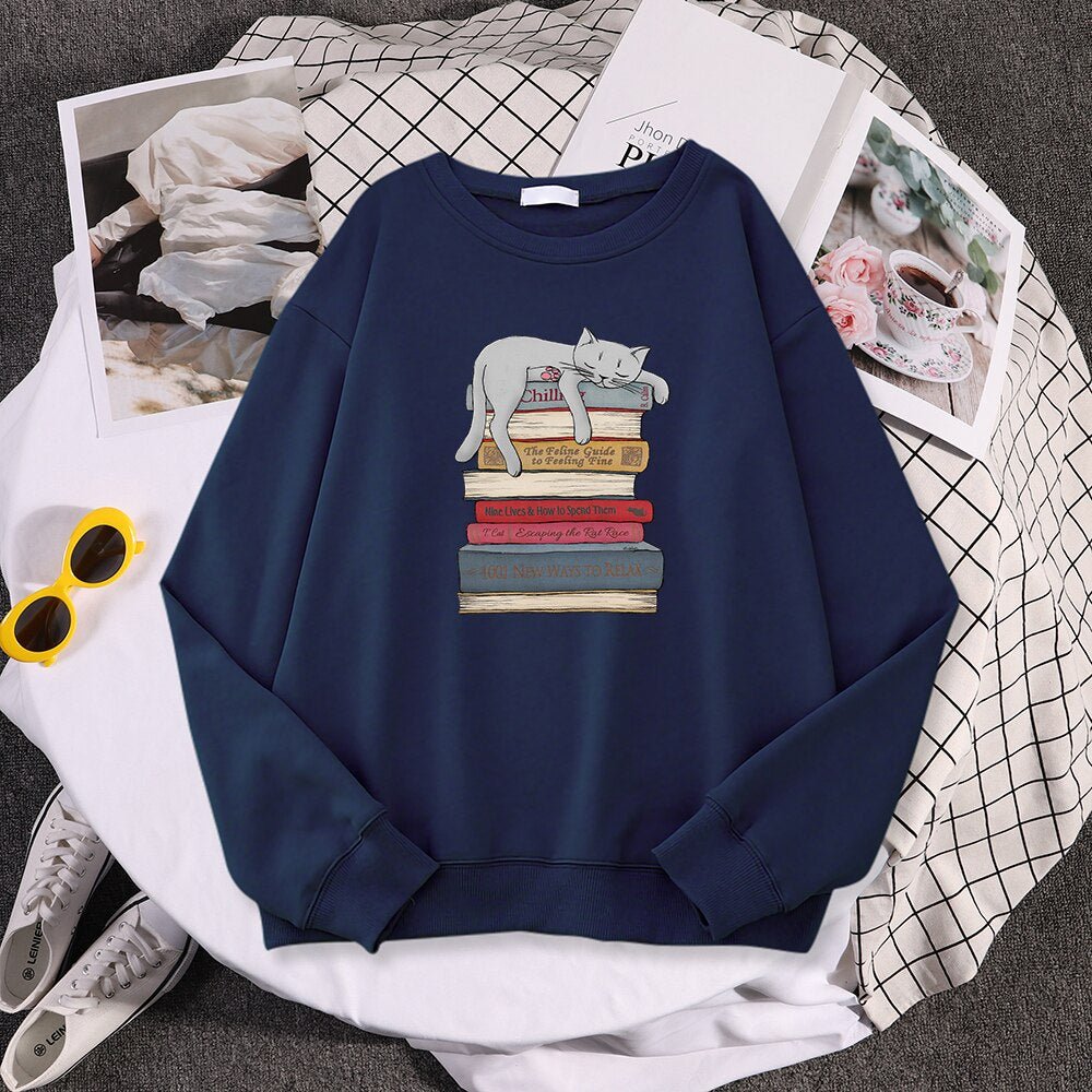 a navy blue sweatshirts with cats on them with a picture of a cat sleeping on a stack of books