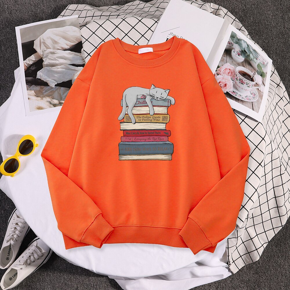 an orange cute cat sweatshirt with a picture of a cat sleeping on a stack of books