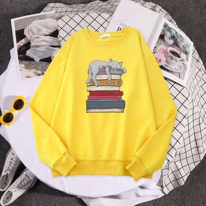 a yellow cat pattern sweater with a picture of a cat sleeping on a stack of books