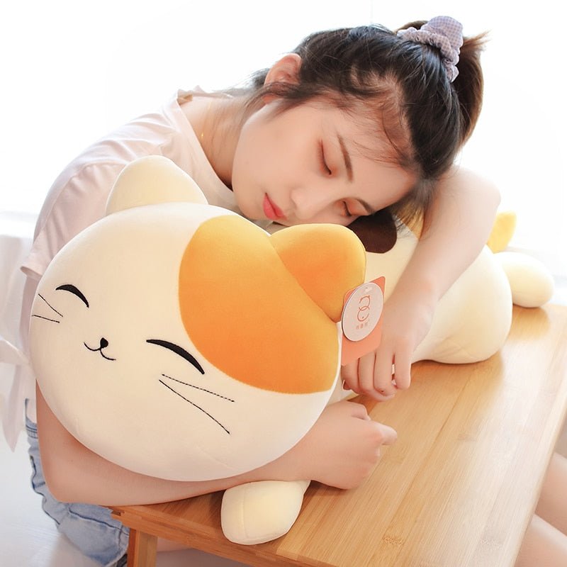 a woman cuddling a smiling calico cat plush