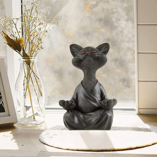 a cat figurine featuring a cat doing meditation in a robe