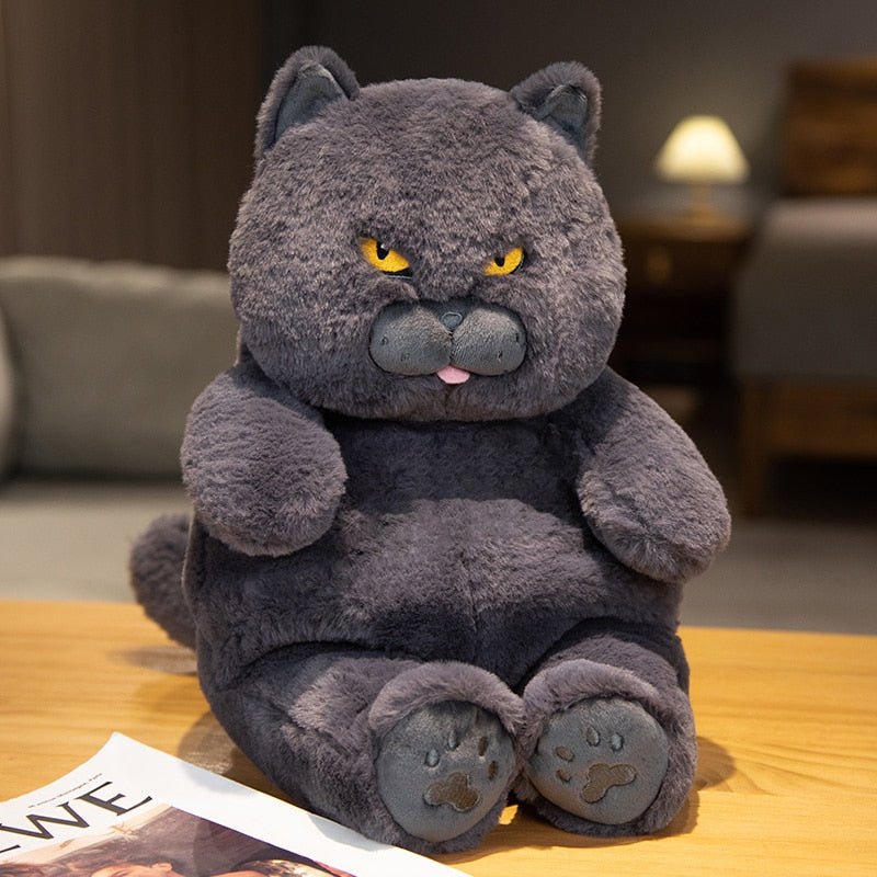 a grey cat plush of an angry cat sitting on a table