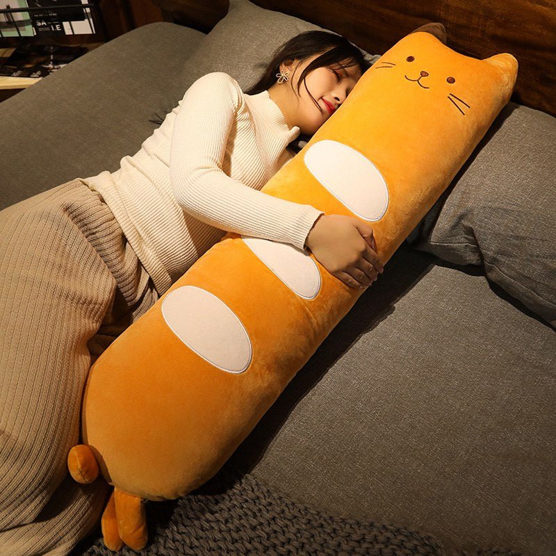 a woman cuddling a long cat plushy on the bed