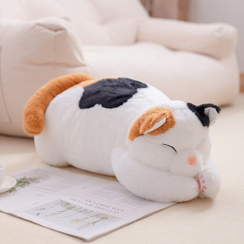 a loafing plush calico cat at a living room