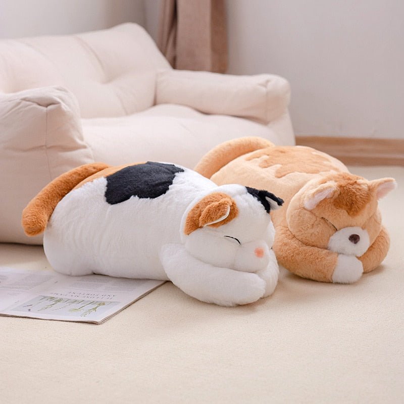 a calico cat plush and orange cat plush are loafing