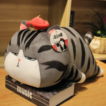 a grey cat plush laying on a table