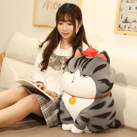a giant size emperor cat plush  having a funny ignoring face sitting besides a girl
