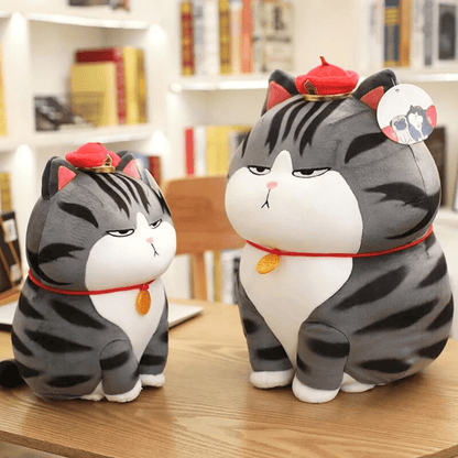two funny cat plush with ignoring faces and dress like a emperor with red hats on them