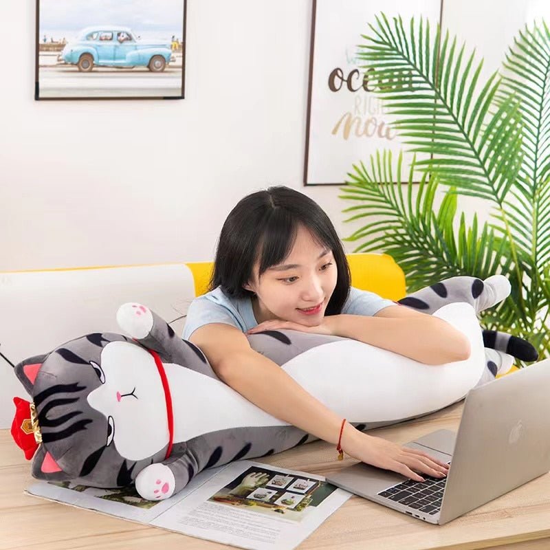 a woman studying while hugging a gray cat plush